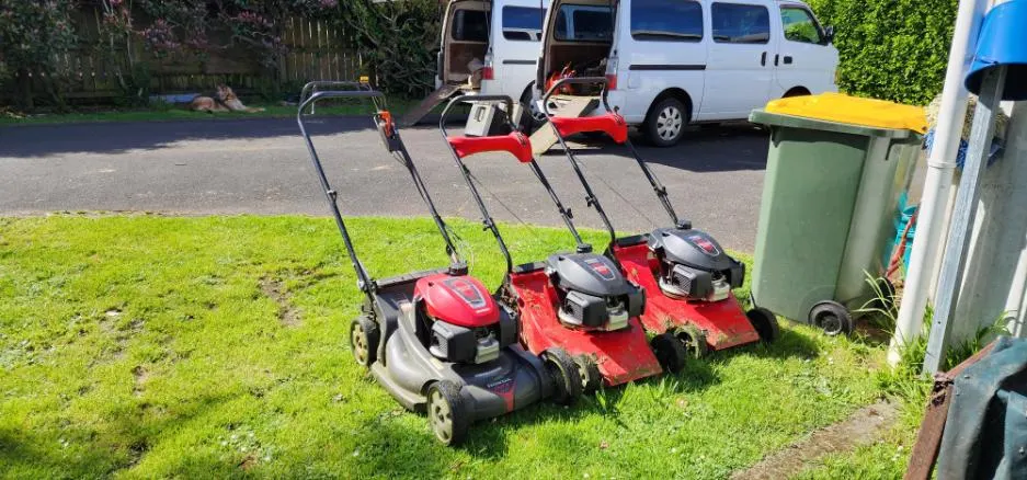 Grass Guardian mowers lined up on a lawn in front of the work van