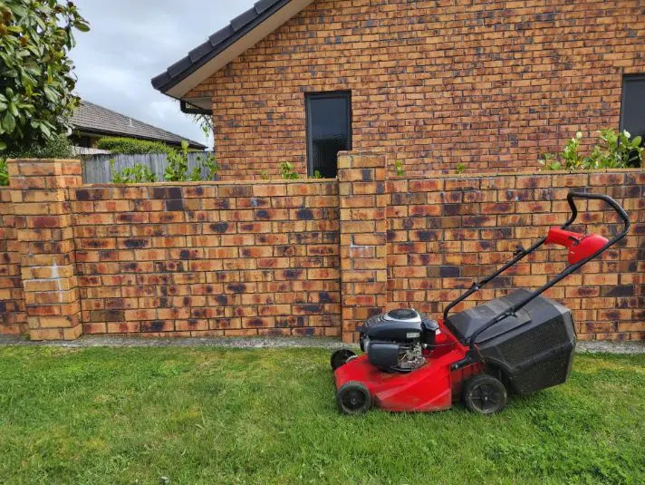 Grass Guardian mower on a tidy front lawn beside a brick wall in Palmerston North